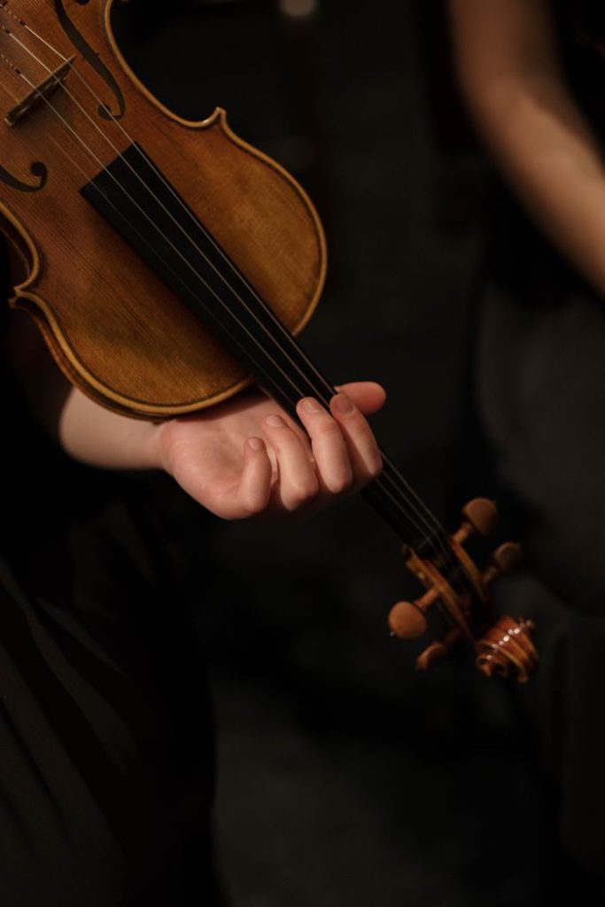 An artistic close-up of a hand holding a violin during a performance.