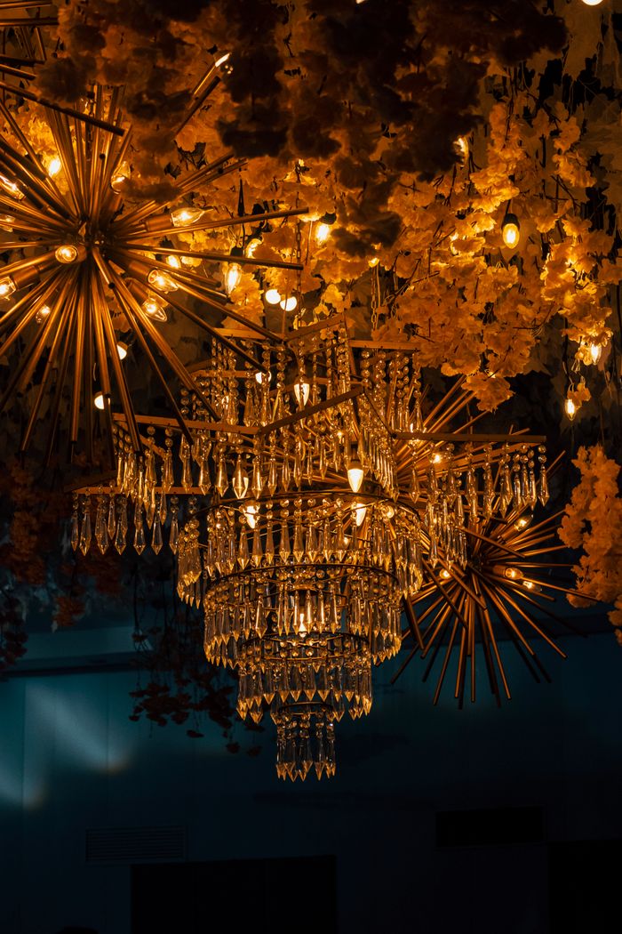 An ornate crystal chandelier with warm illumination, surrounded by golden decor.