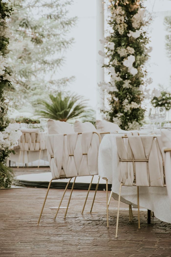 Beautifully decorated wedding venue with elegant chairs and floral arrangements.