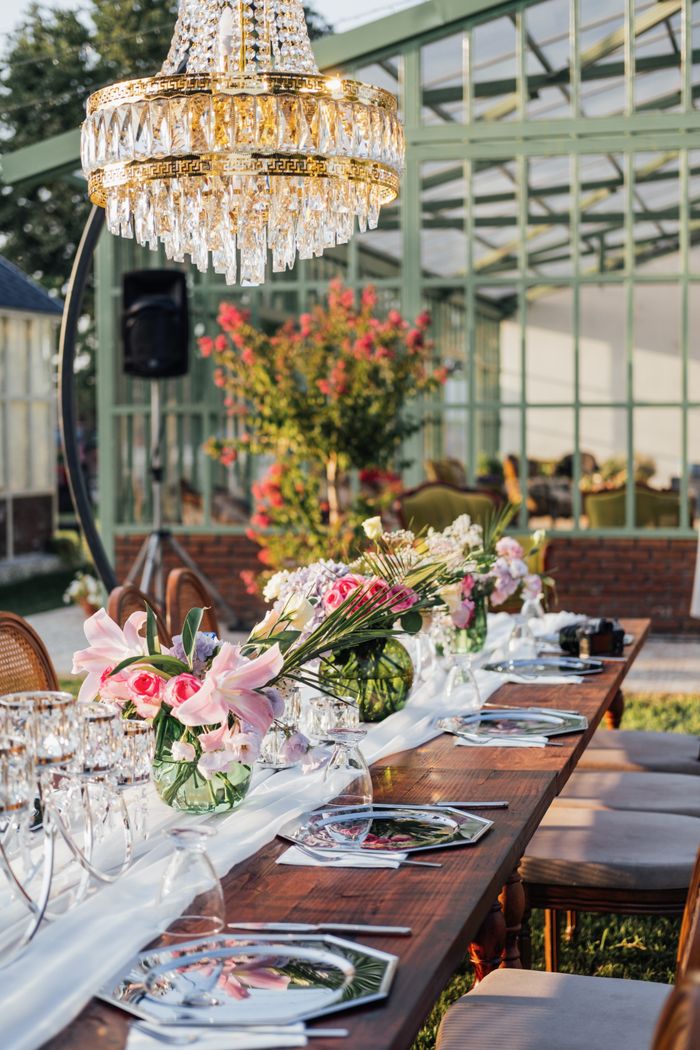Luxurious garden dining table with chandelier and floral decor, perfect for events.