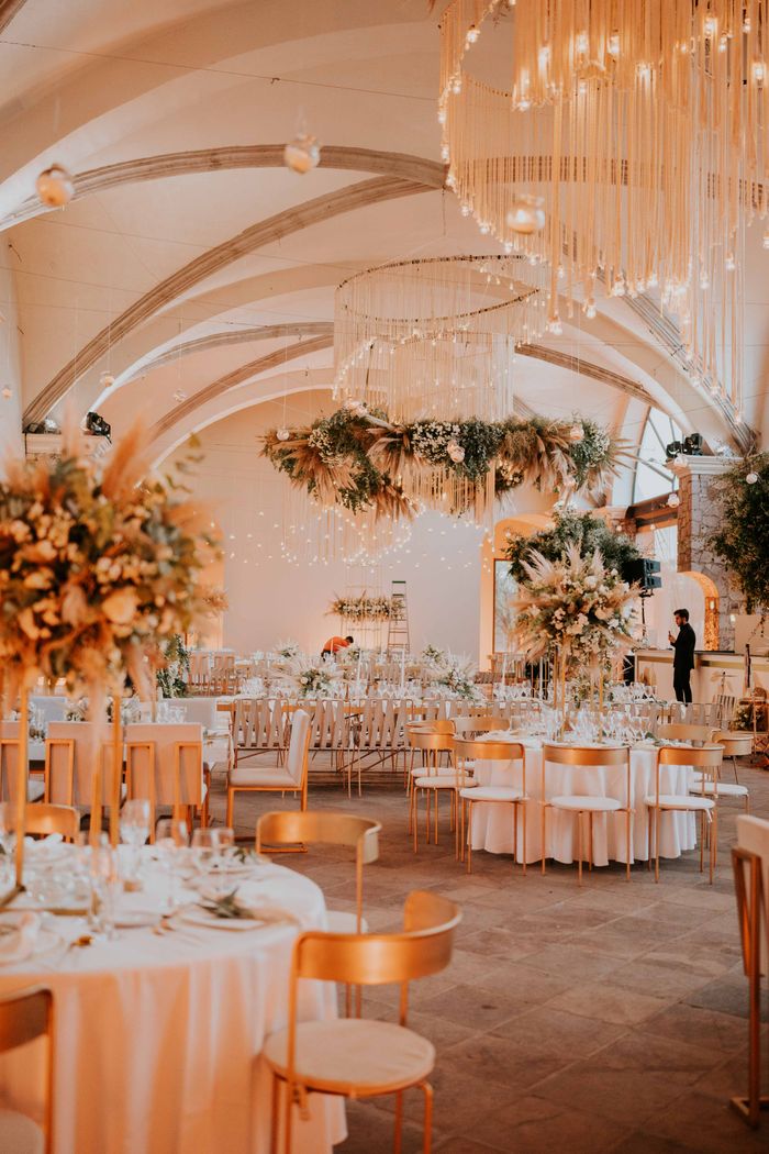 Stunning wedding reception setup with white tablecloths and floral chandeliers in an elegant indoor venue.