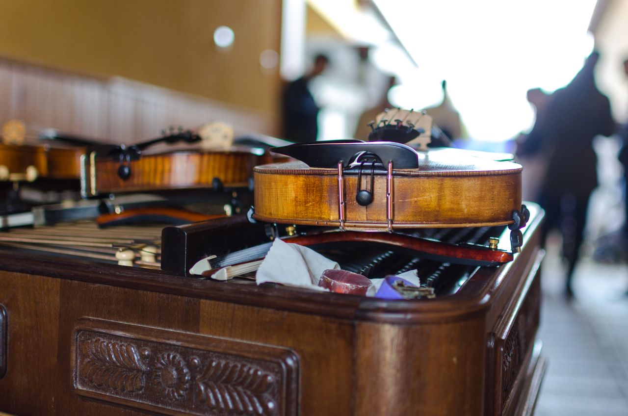 A detailed view of violins resting on a wooden table indoors, suggesting musical preparation.