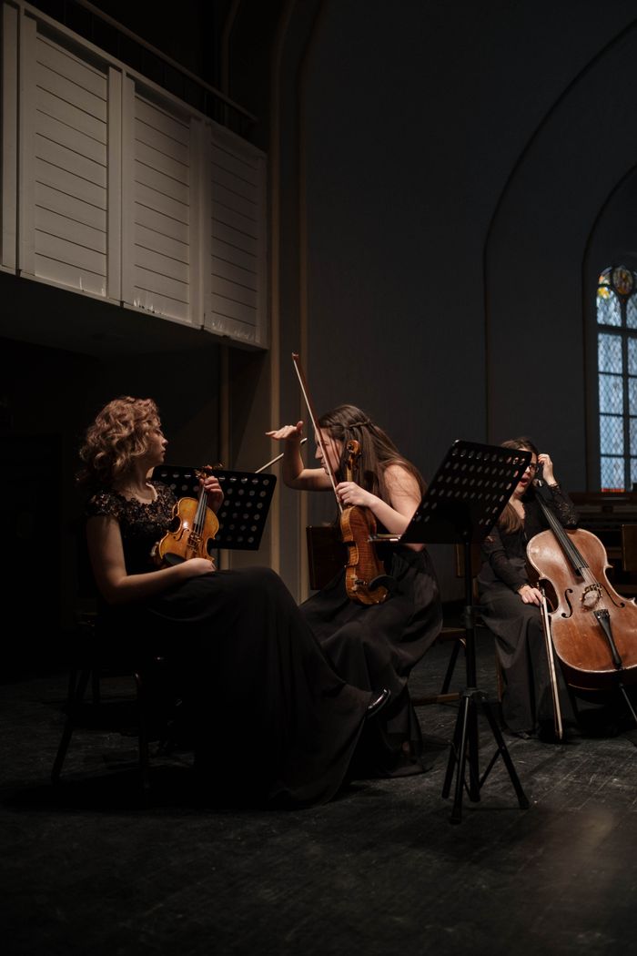 Women musicians performing a symphony with violins and cello indoors.