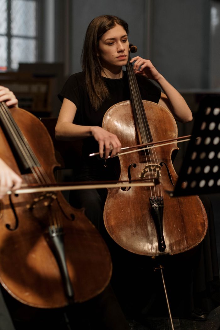 Professional female cellist performing with focus on her cello during a classical symphony.