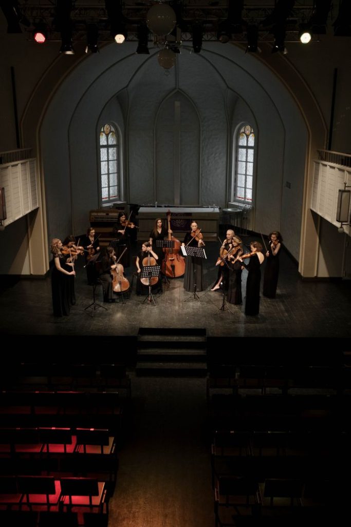 String ensemble performing on stage in a historic church setting, captured from above.